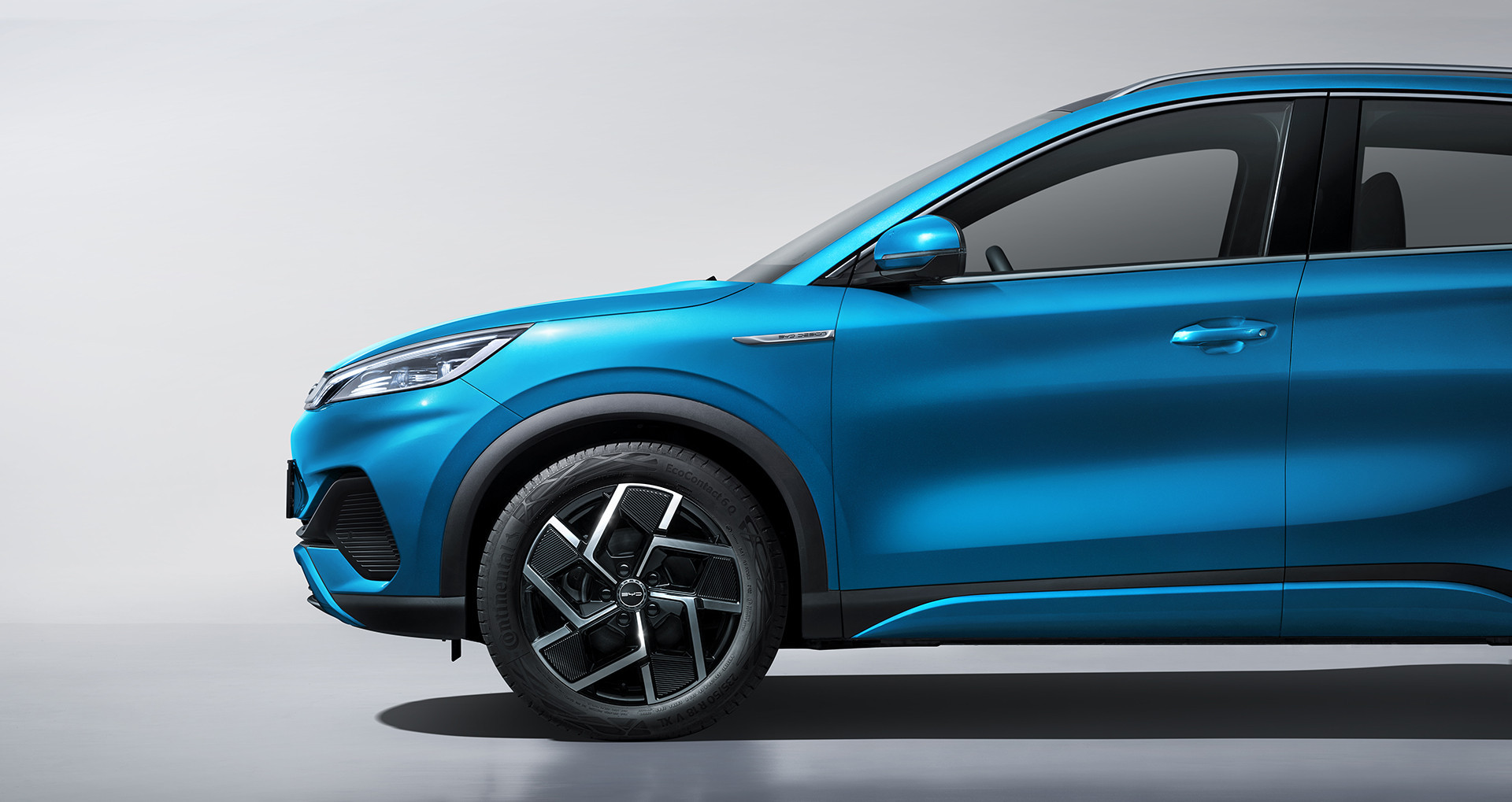 A photograph of a Surfing Blue BYD Atto 3 from the side, cropped to only show the front half of the car